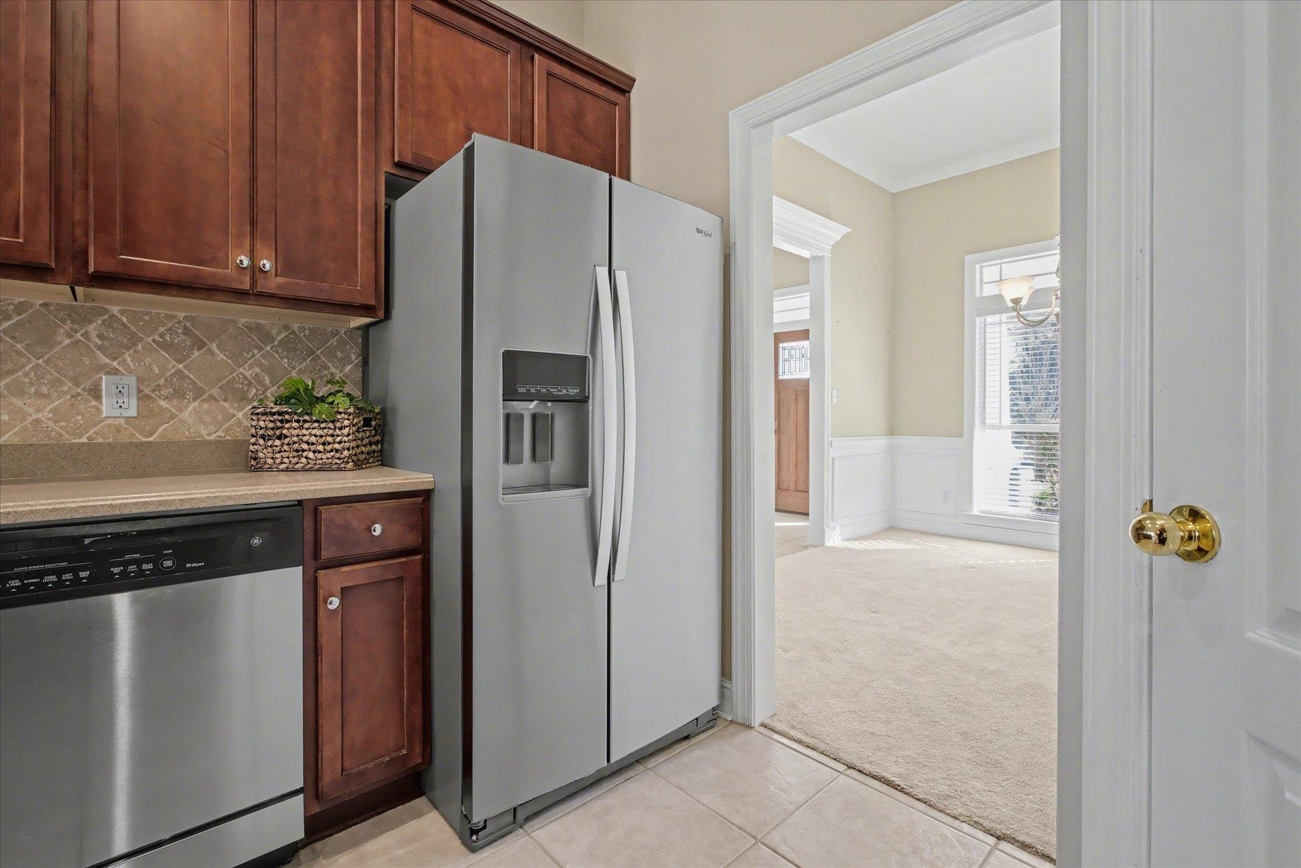 Kitchen with dark wood cabinets and stainless steel appliances beside a bright adjoining room.
