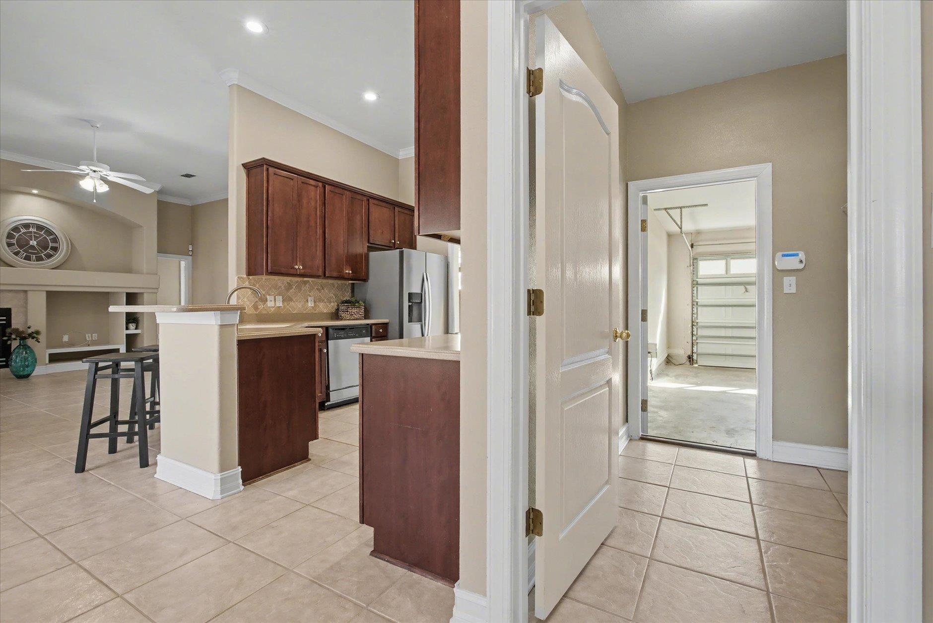 Kitchen with dark wood cabinets, stainless steel appliances, and a tiled floor beside the garage entry.