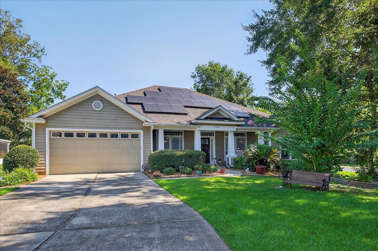 Gray single-story home with rooftop solar panels, a two-car garage, and a landscaped front lawn.