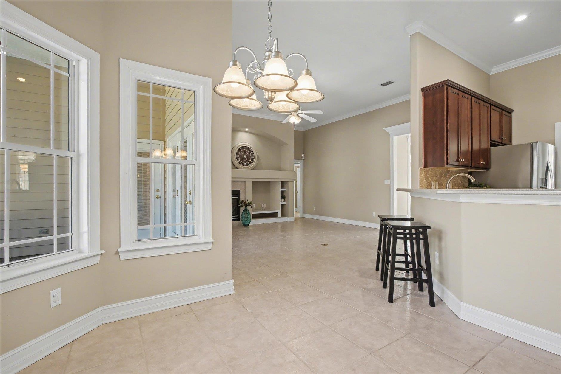 Open-plan kitchen with a tiled floor, breakfast bar, dark wood cabinets, and an adjoining living area with a fireplace.
