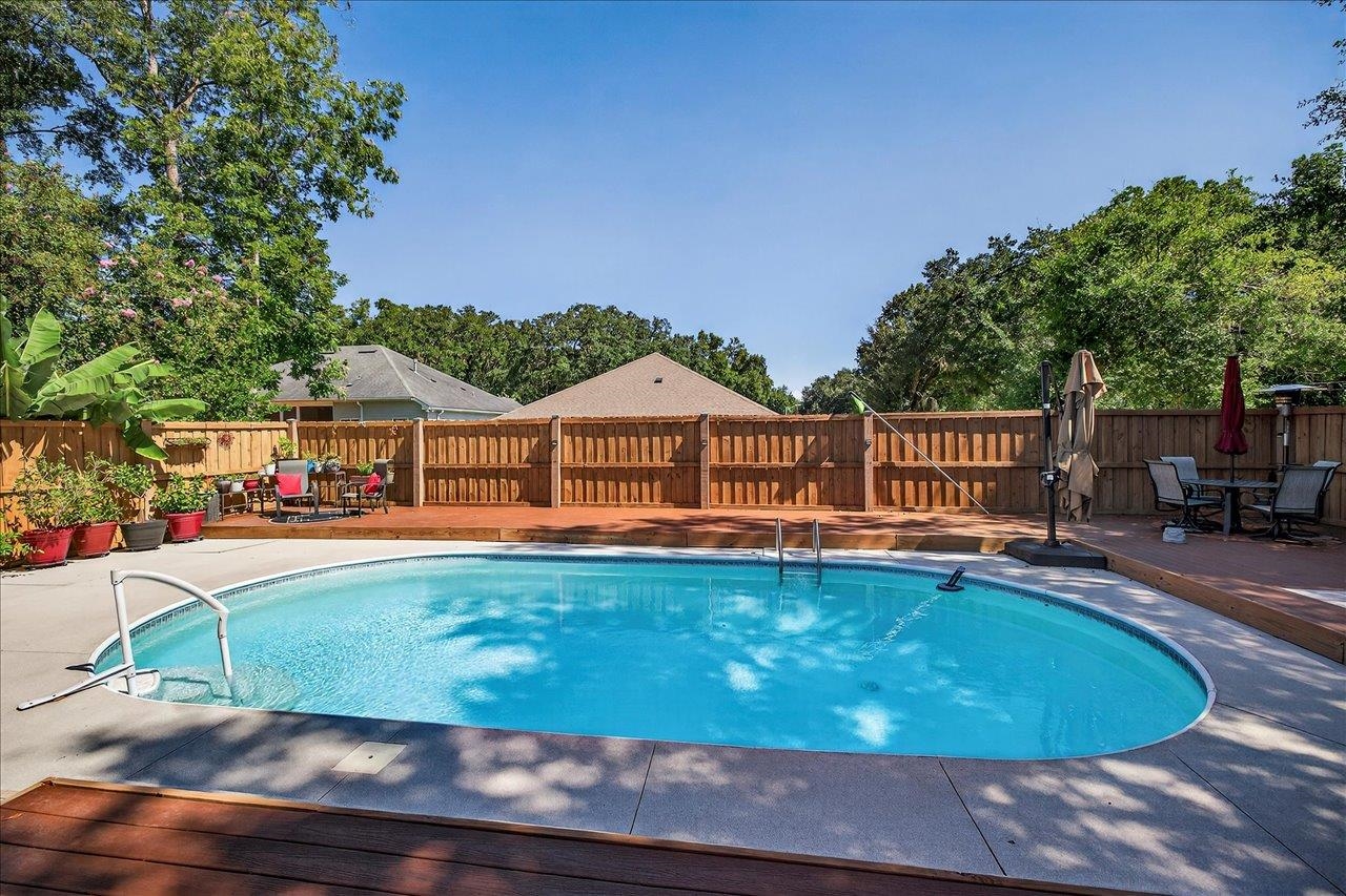 Backyard swimming pool with a wooden privacy fence, patio, and outdoor seating.