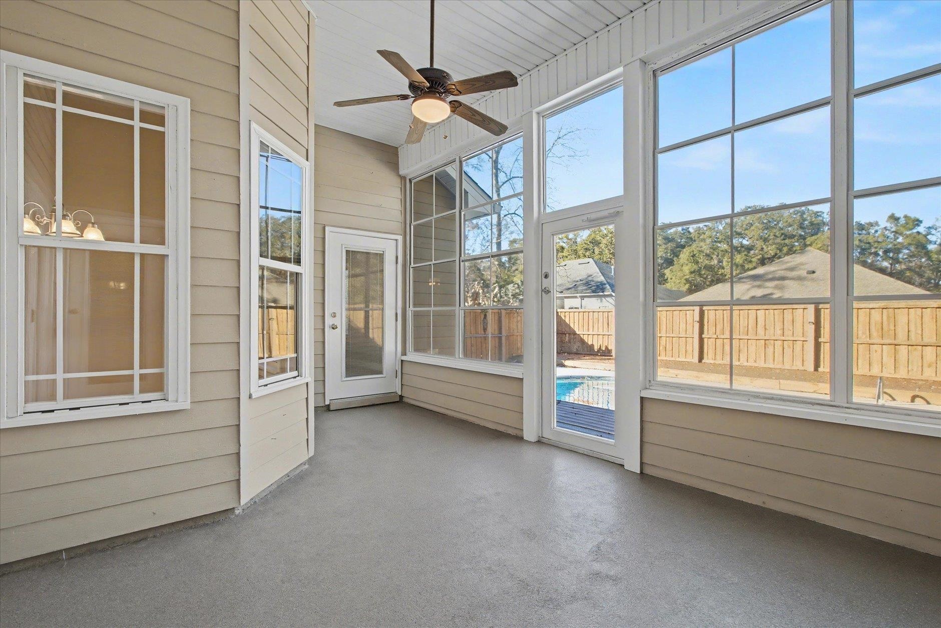 Screened porch with large windows, a ceiling fan, and a view of the backyard pool.