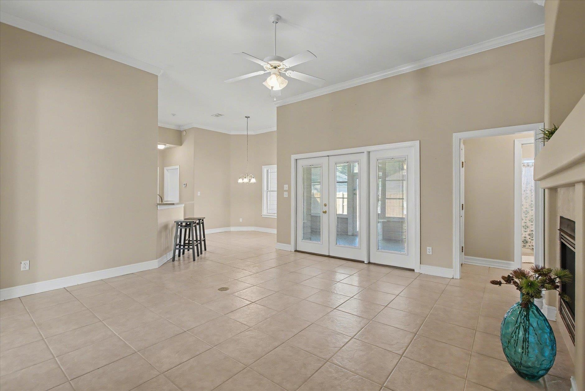 Open living and dining area with tiled floors, French doors, and a breakfast bar.
