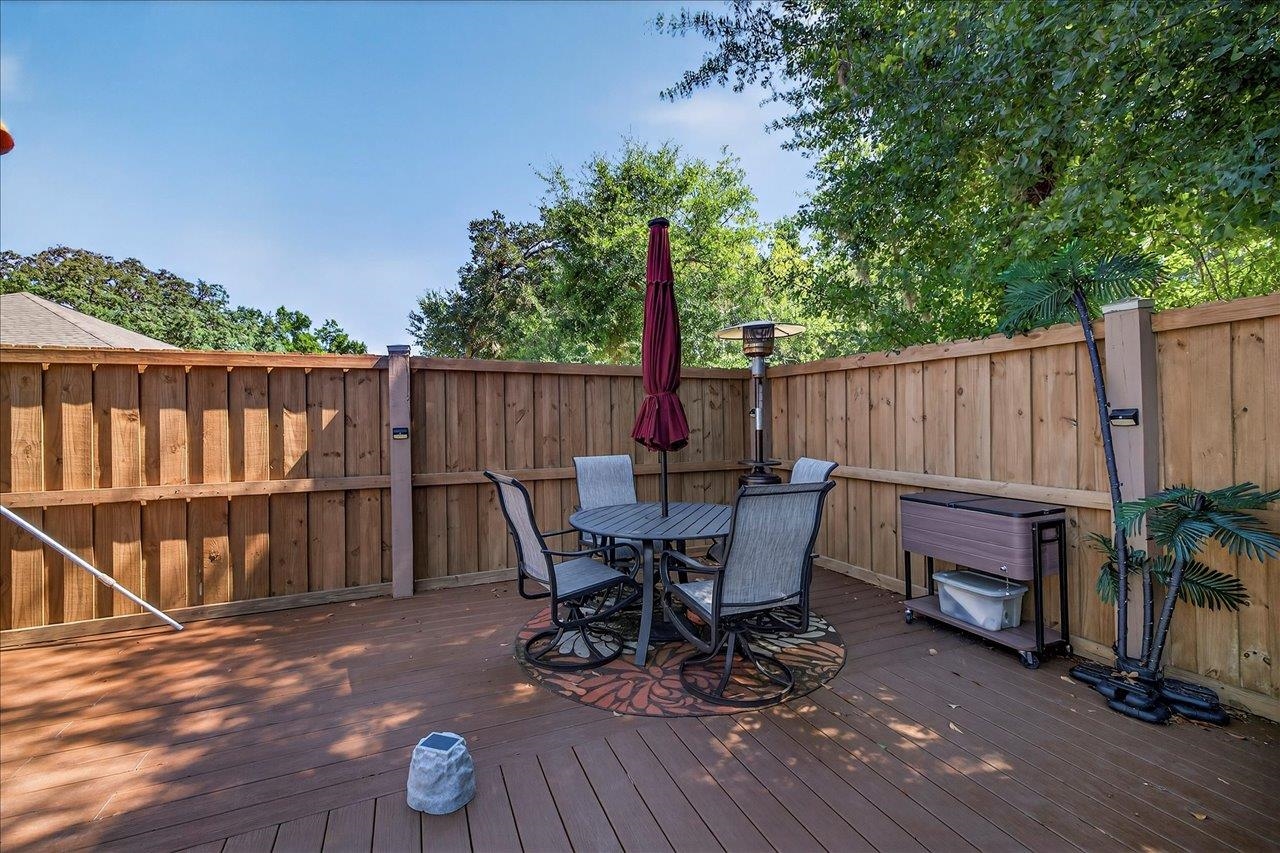 Fenced backyard deck with outdoor dining set, burgundy umbrella, and patio heater.