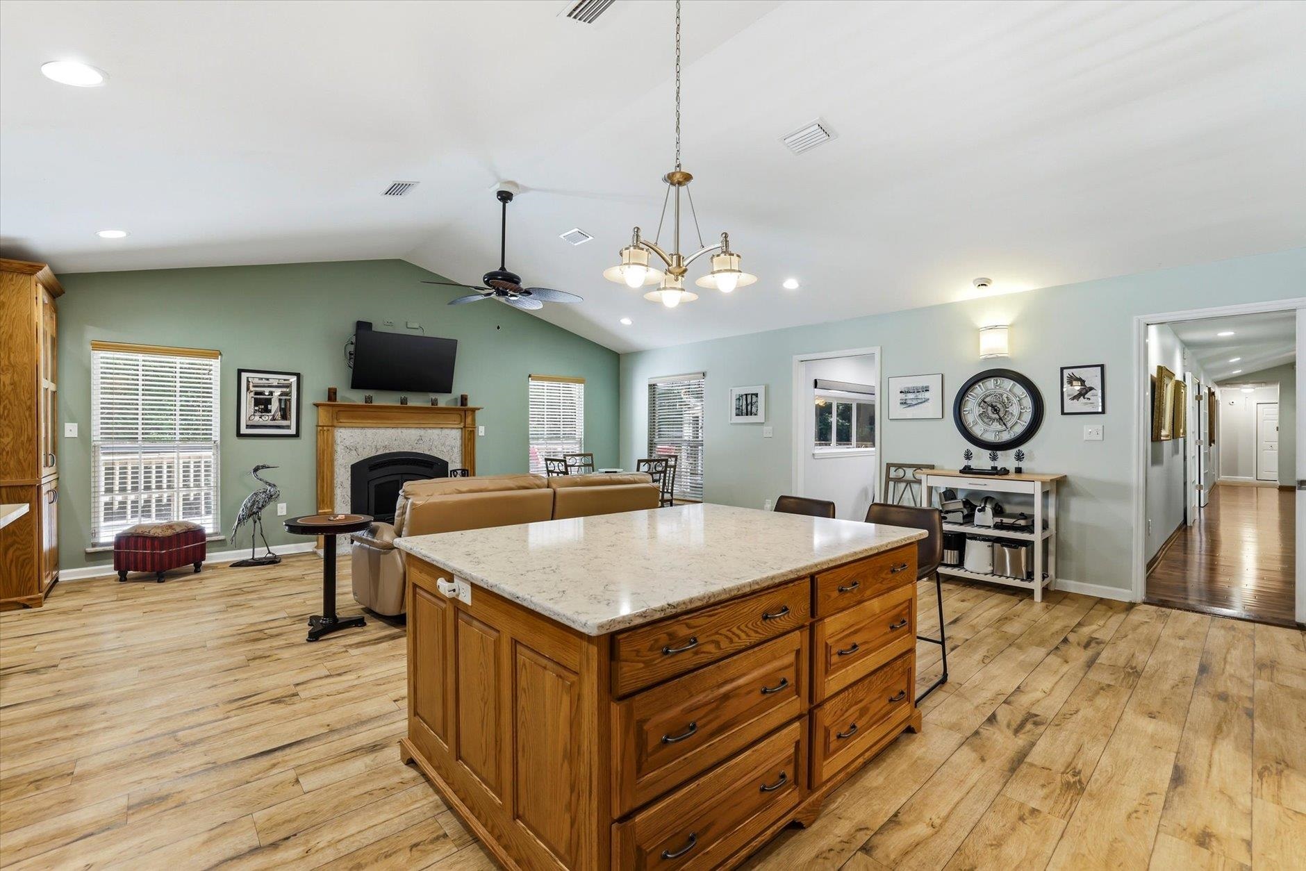 Open-plan kitchen with a large wood island, stone countertop, and fireplace.