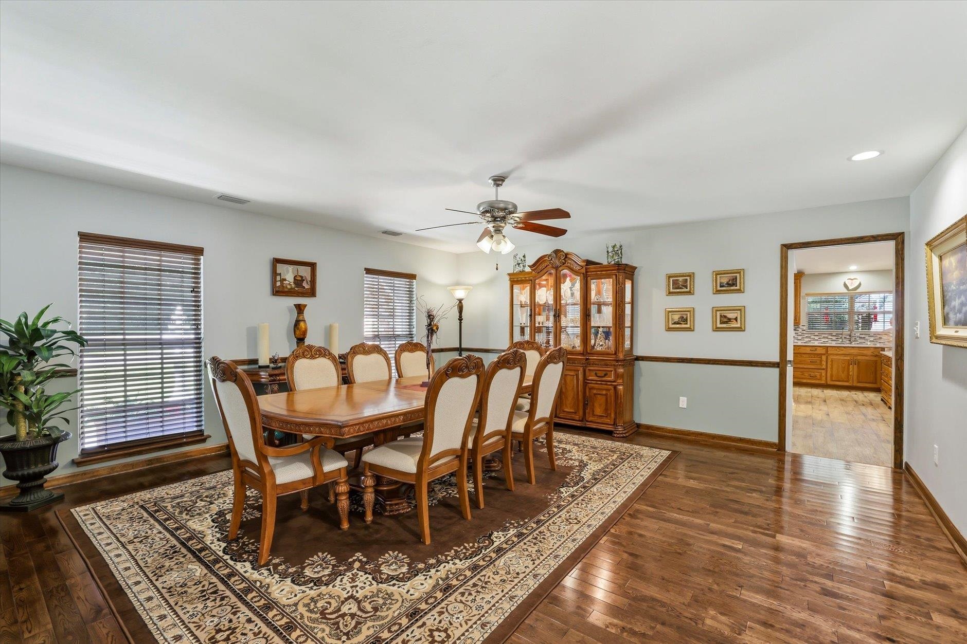 Dining room with carved wooden table, upholstered chairs, and glass-front china cabinet.