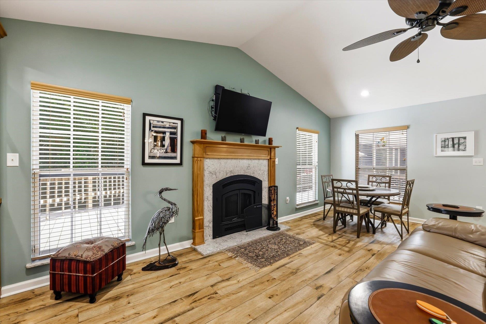 Living room with a wood-trimmed fireplace, vaulted ceiling, and adjoining dining area.