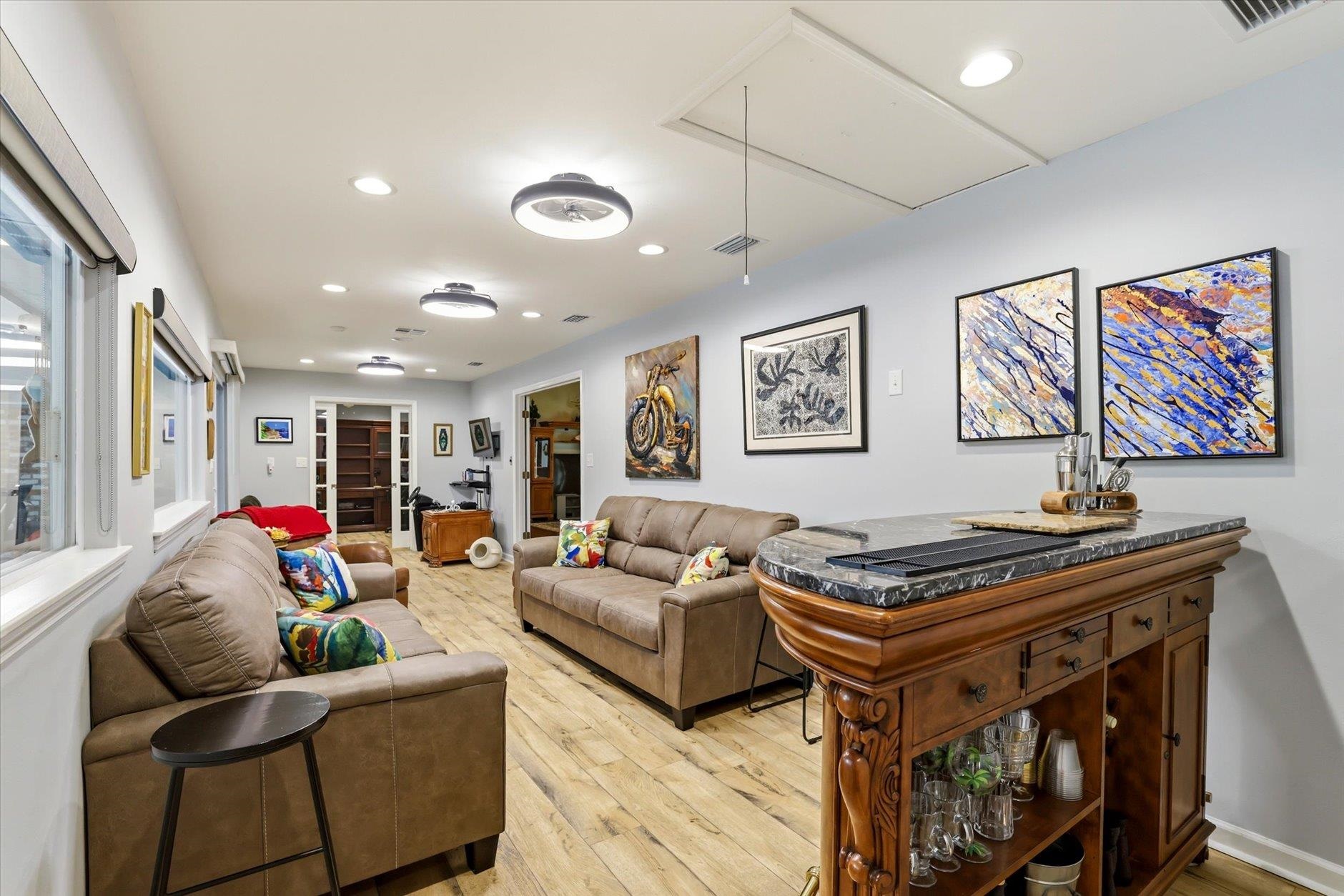 Furnished living room with leather sofas and an ornate wooden bar cabinet.