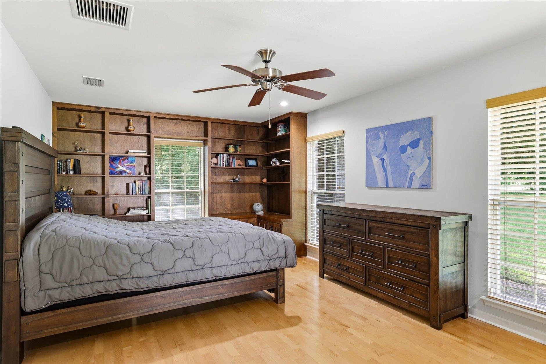 Bedroom with a wooden bed, built-in bookshelves, and matching dresser.