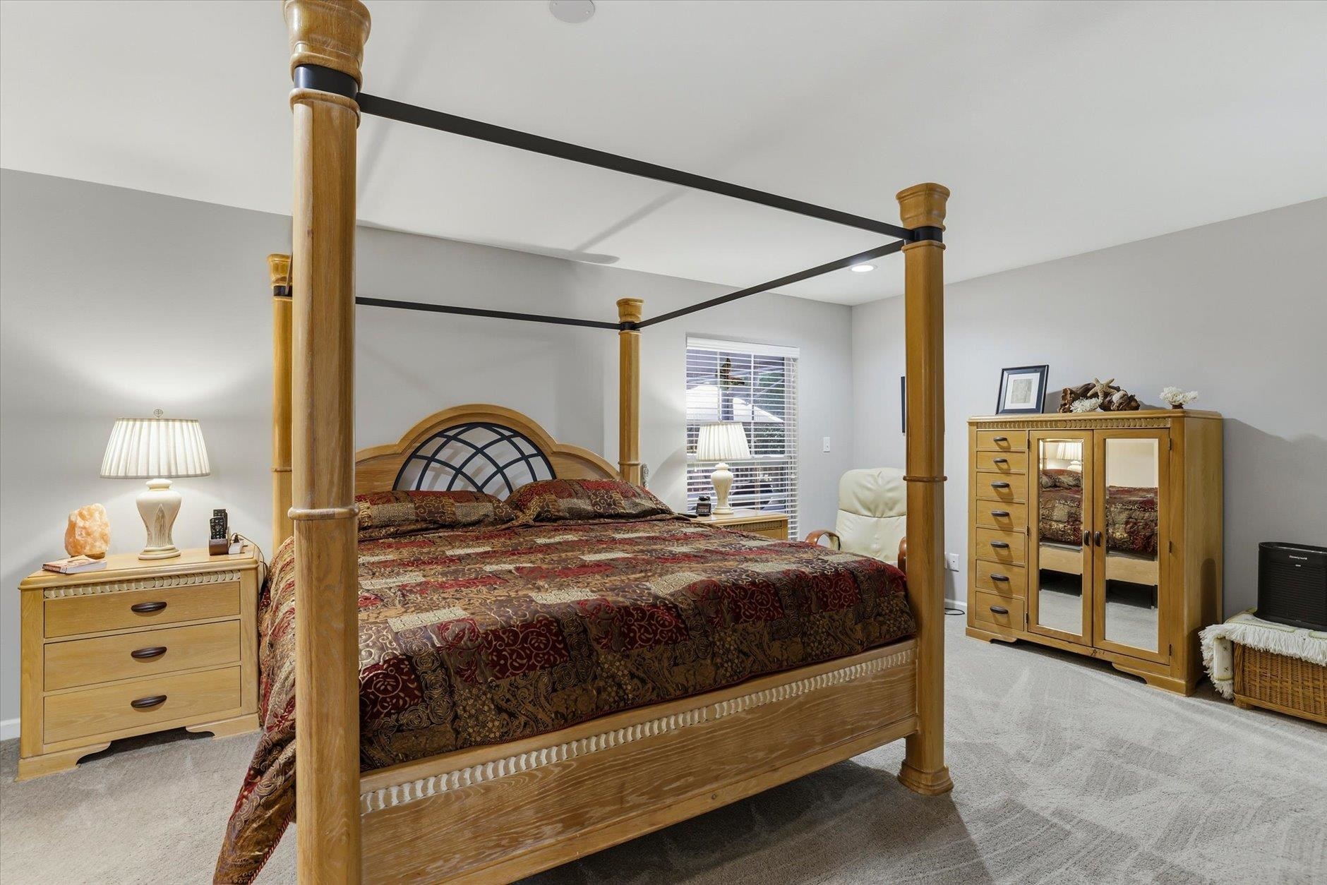 Bedroom with a wooden four-poster bed, patterned bedding, and mirrored armoire.