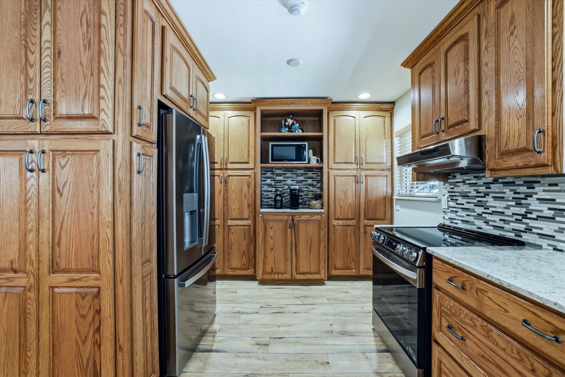Kitchen with oak cabinets, stainless steel appliances, and a gray-and-white mosaic backsplash.
