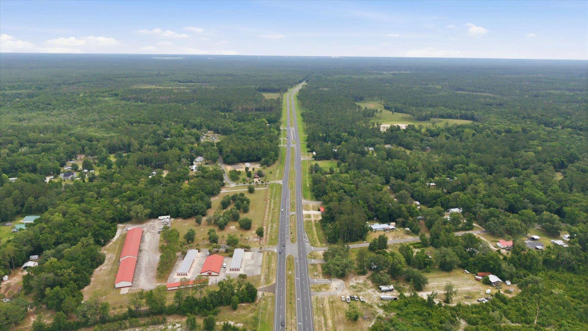Aerial view of wooded land along Crawfordville Highway, with scattered buildings and a divided road.