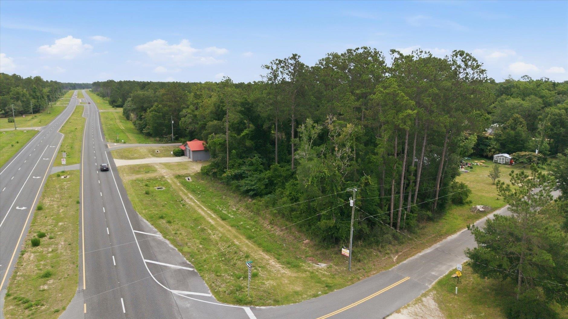 Wooded vacant parcel between a divided highway and a two-lane road.