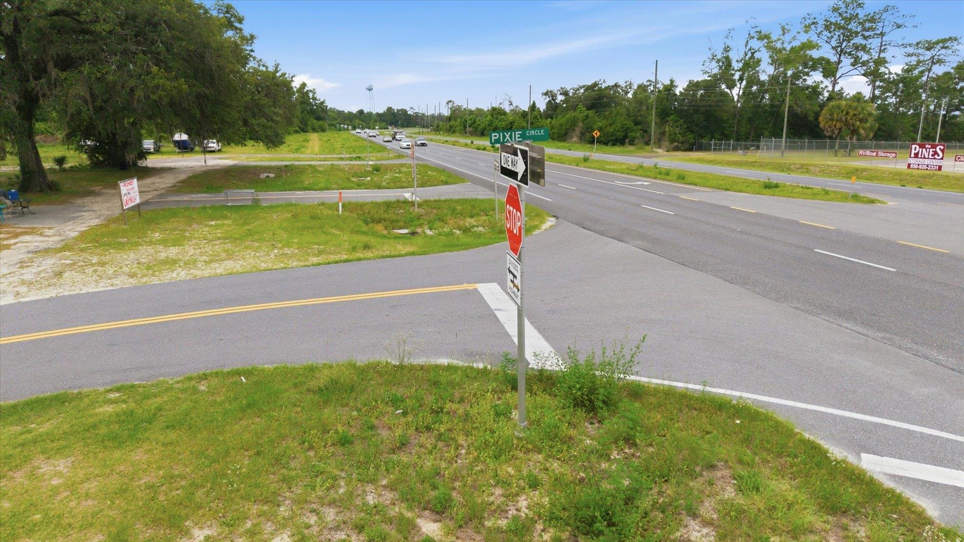 Open grassy property beside a highway intersection, with Pixie Circle and stop signs.
