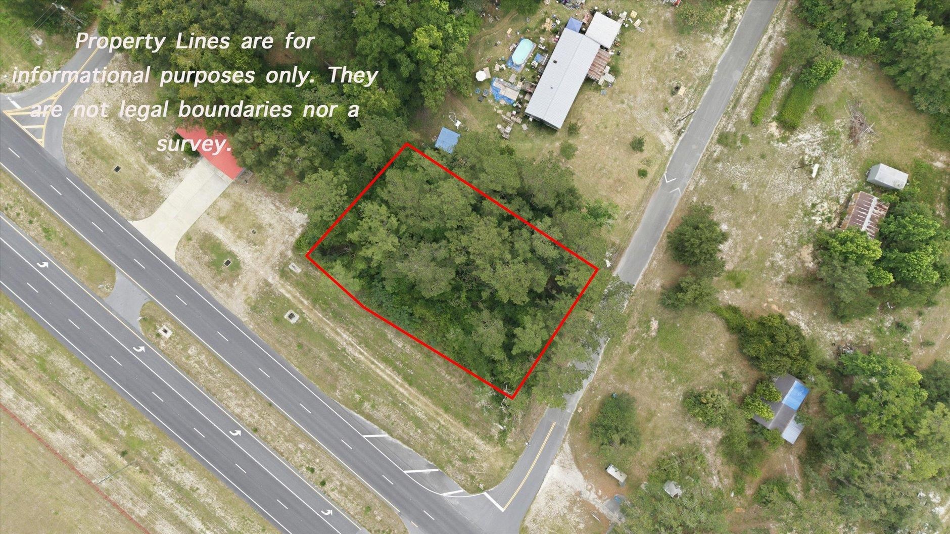 Aerial view of a wooded parcel outlined in red beside a highway and intersecting road.