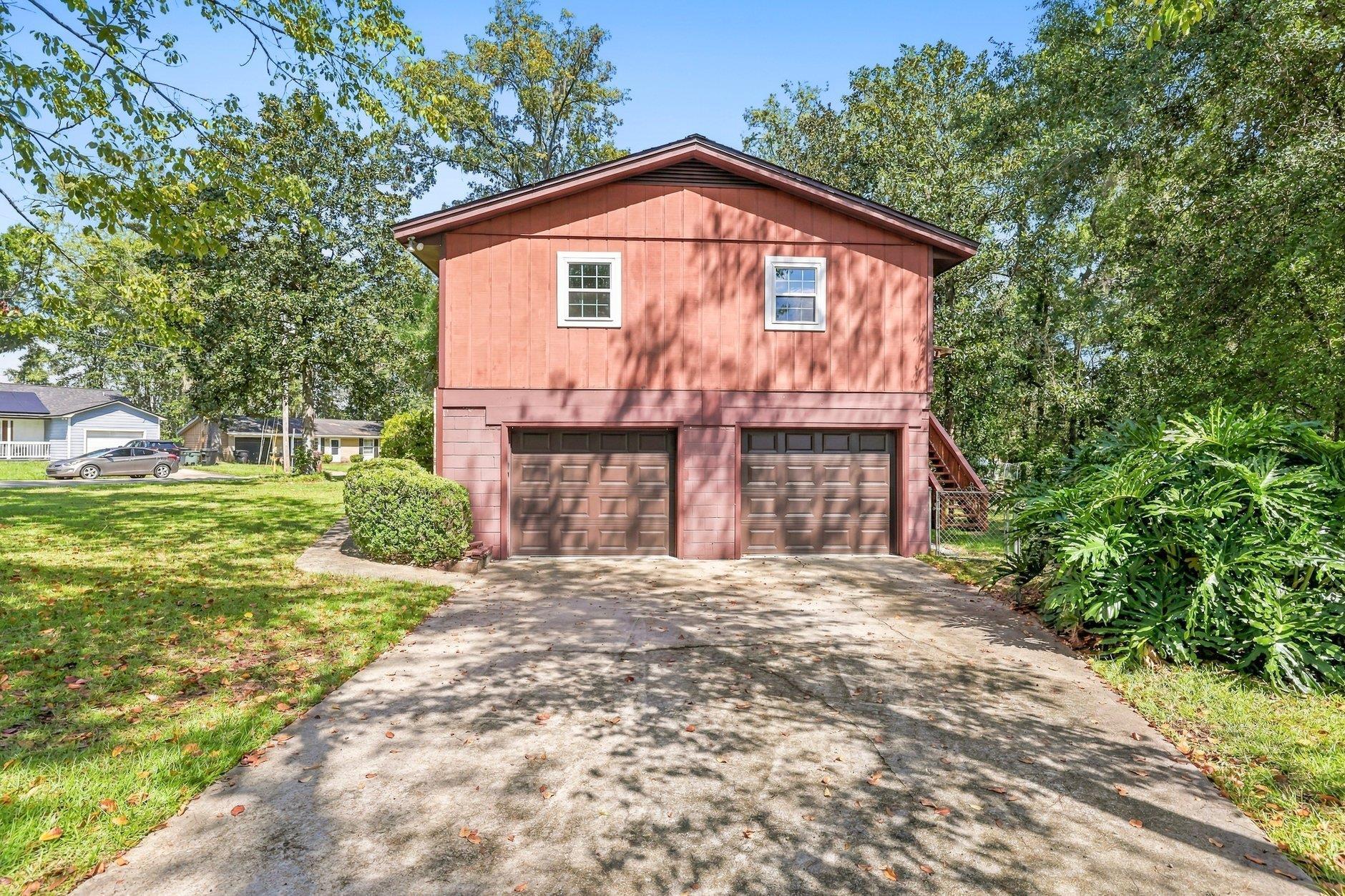 Red two-story home with two garage doors and a wide concrete driveway.