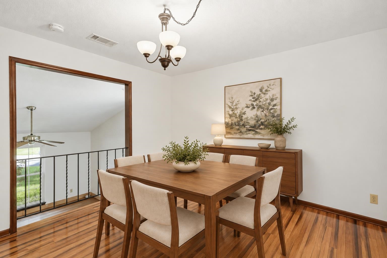Dining room with a wooden table, upholstered chairs, and an open railing overlooking the lower level.