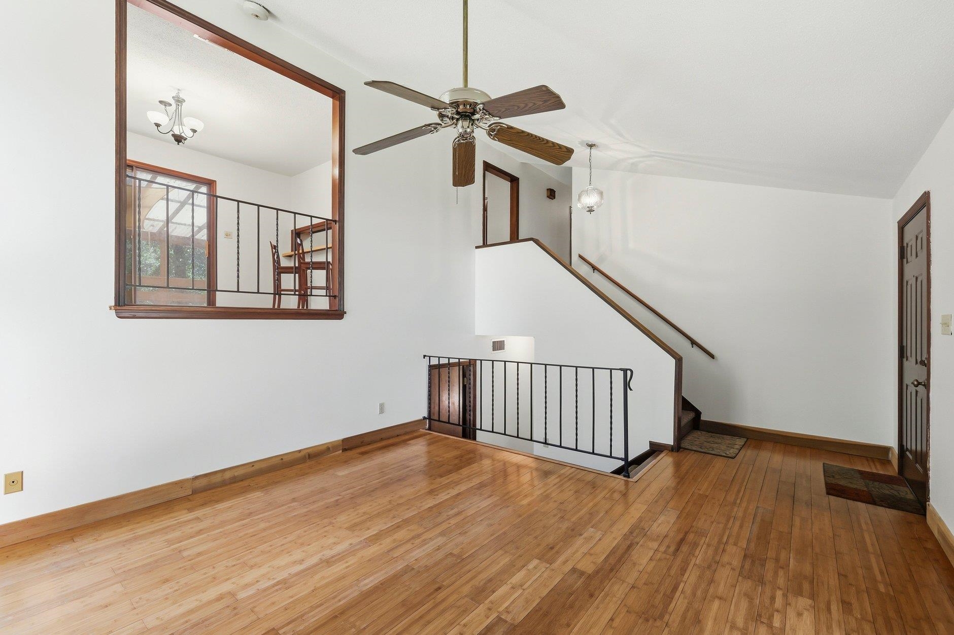 Two-story living room with hardwood floors, a ceiling fan, and an overlooking dining area.