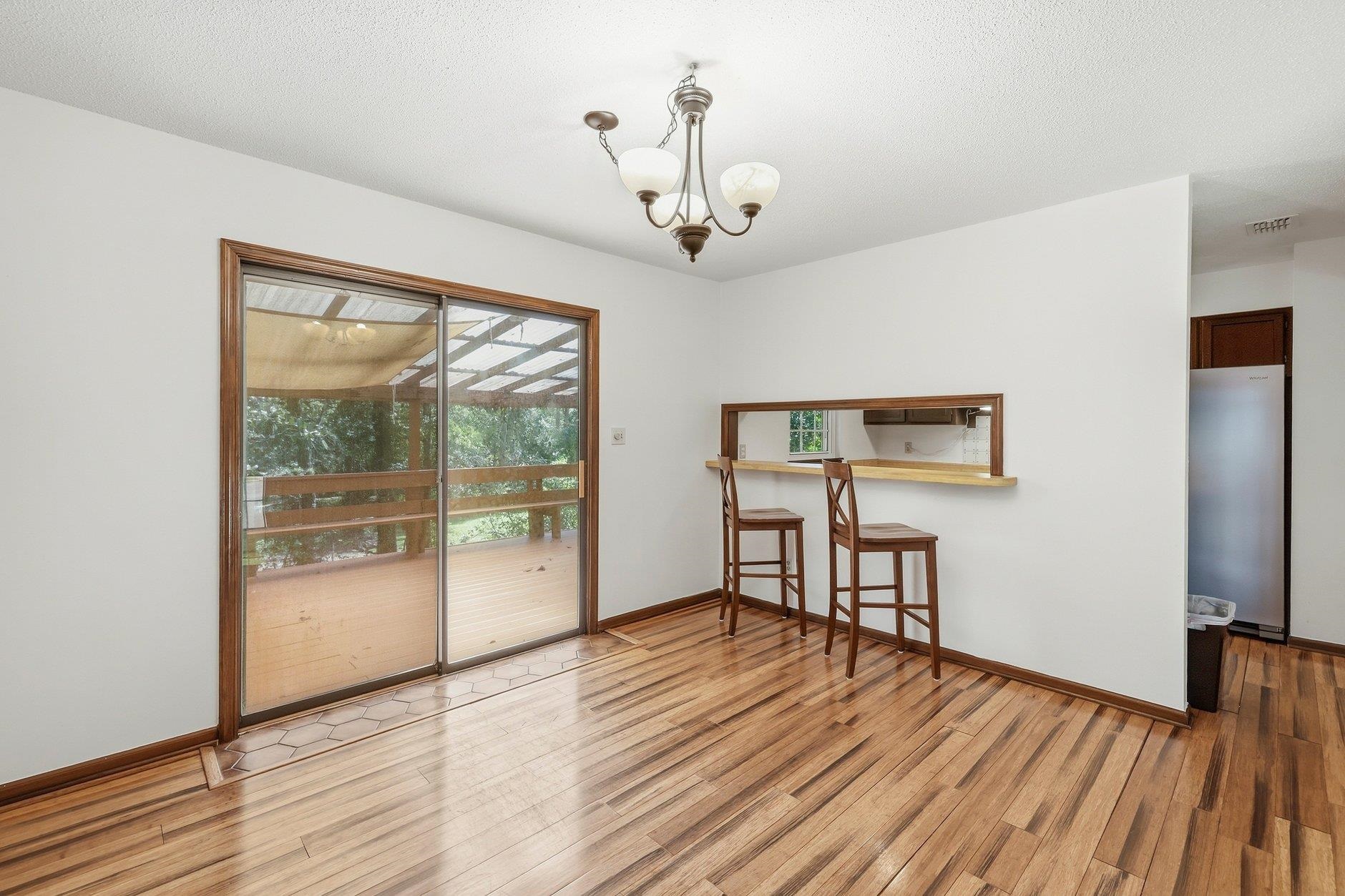 Dining area with hardwood floors, a kitchen pass-through, and sliding doors to a covered deck.