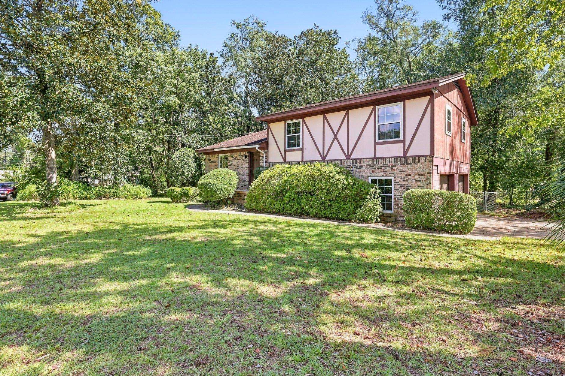 Two-story home with red-and-white half-timbered siding, brick lower level, and a tree-lined lawn.