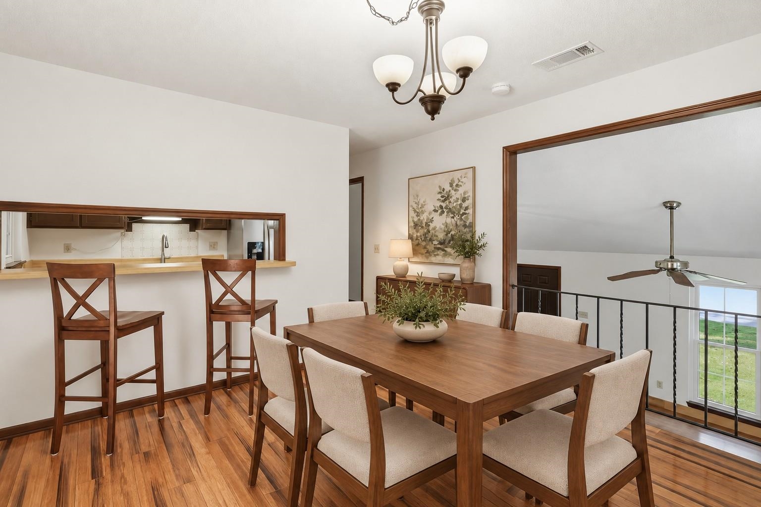 Dining room with a wood table, upholstered chairs, hardwood floors, and a kitchen pass-through.