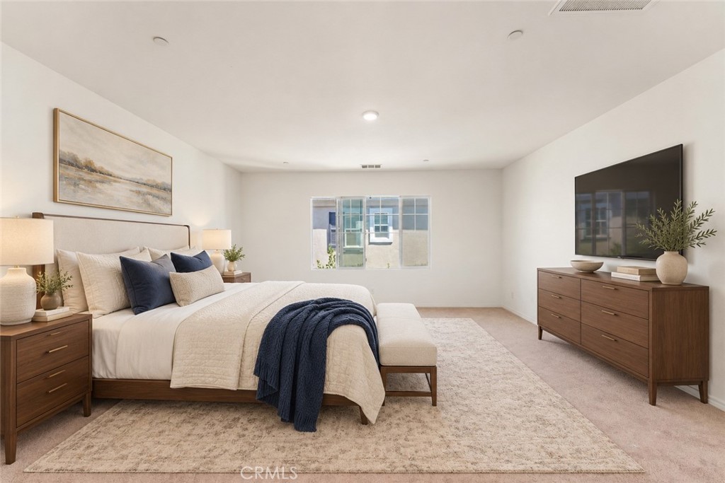 Staged bedroom with a king-size bed, navy accents, and a television above a wooden dresser.