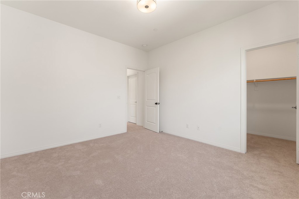 Empty bedroom with beige carpet and an open closet.