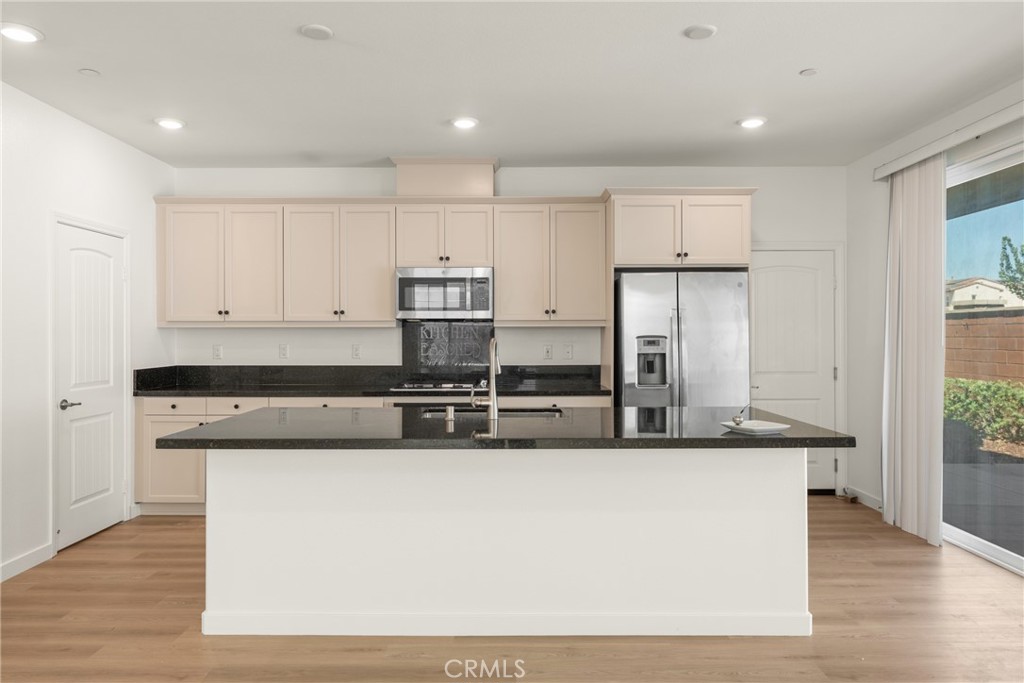 Vacant kitchen with a large dark-counter island, cream cabinets, and stainless steel appliances.