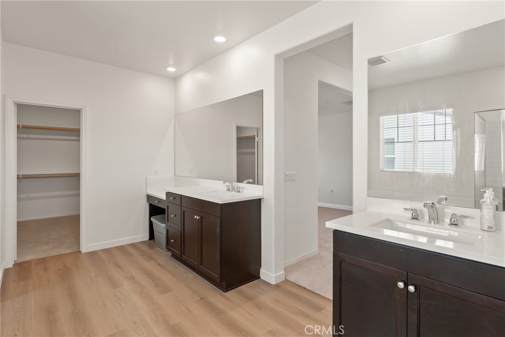 Bathroom with two dark-wood vanities, large mirrors, and an open closet.