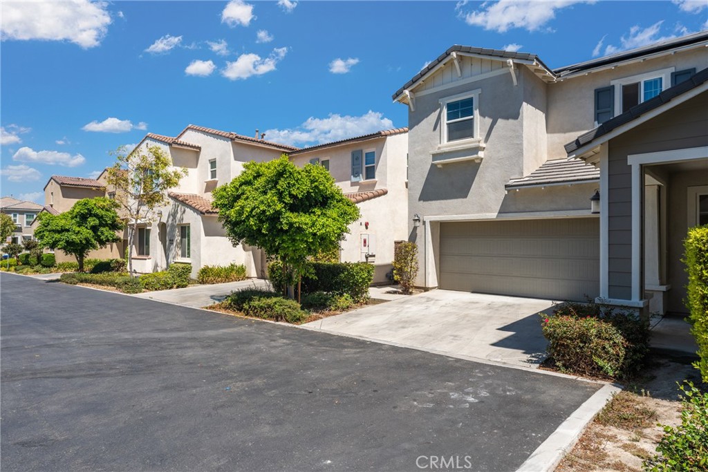 Two-story stucco home with a tiled roof, single garage, and landscaped front yard.