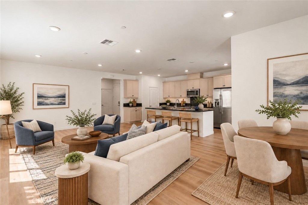 Open-plan living room and kitchen with a cream sofa, blue armchairs, and a kitchen island.