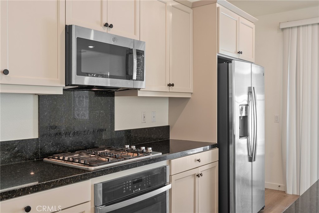 Kitchen with dark granite counters, white cabinetry, and stainless-steel appliances.