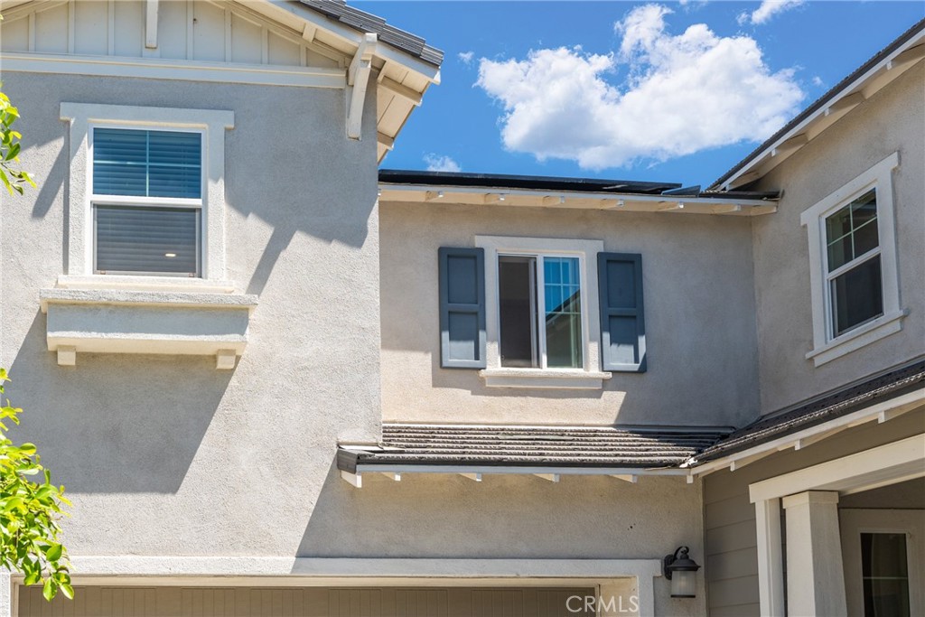 Two-story stucco home exterior with blue shutters and intersecting rooflines.