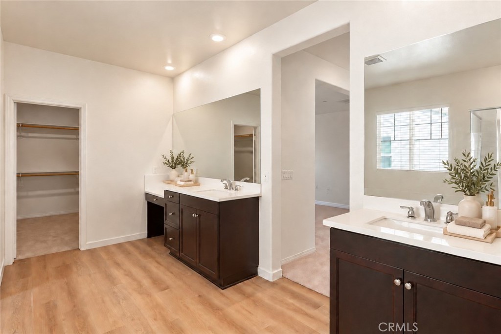 Bathroom with two dark wood vanities, large mirrors, and an open walk-in closet.
