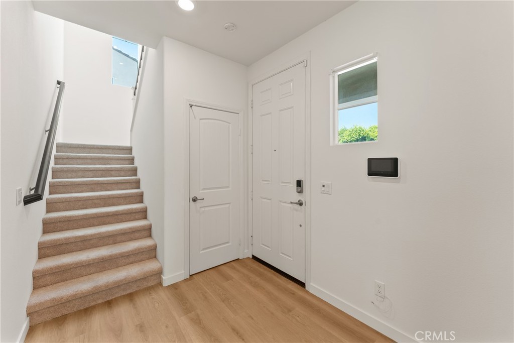 Entry foyer with a carpeted staircase, light wood flooring, and white doors.