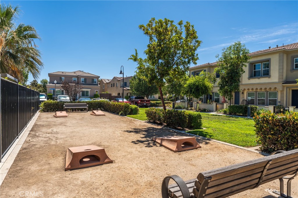 Residential courtyard with a sandy recreation area, wooden structures, benches, and surrounding homes.