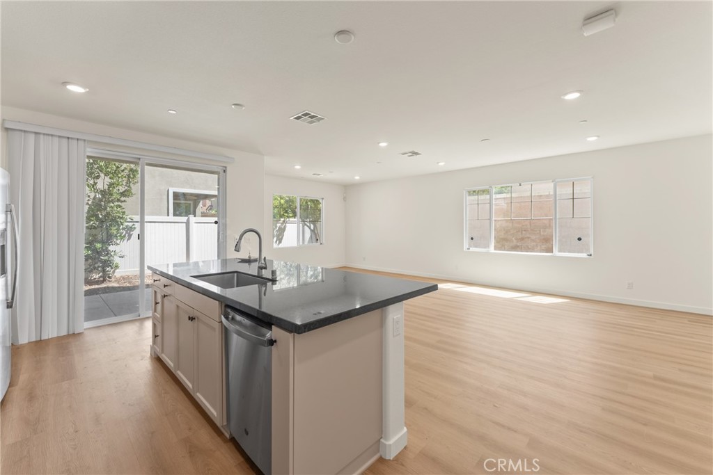 Vacant open-plan kitchen with a large dark stone island and sliding doors to a fenced patio.