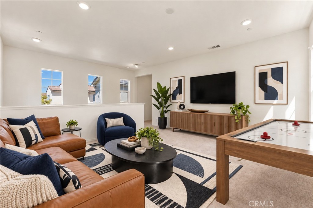 Living room with leather sectional, navy chair, geometric rug, and shuffleboard table.