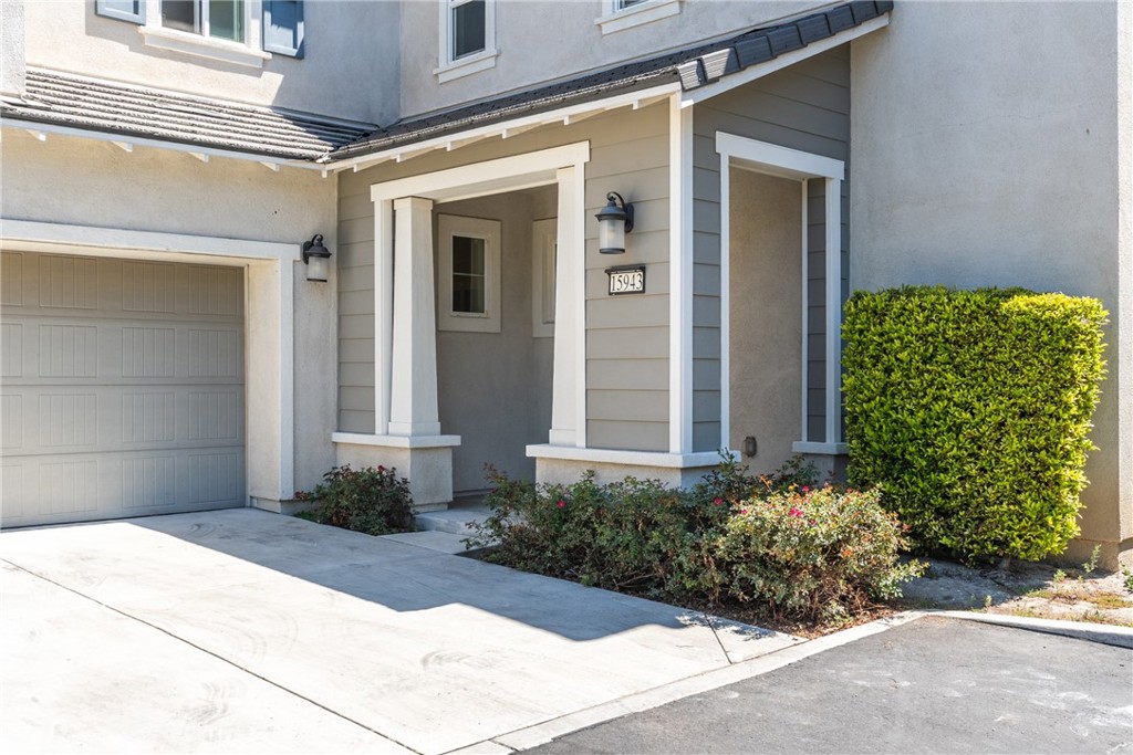 Home entrance with attached garage, covered porch, and address number 15943.