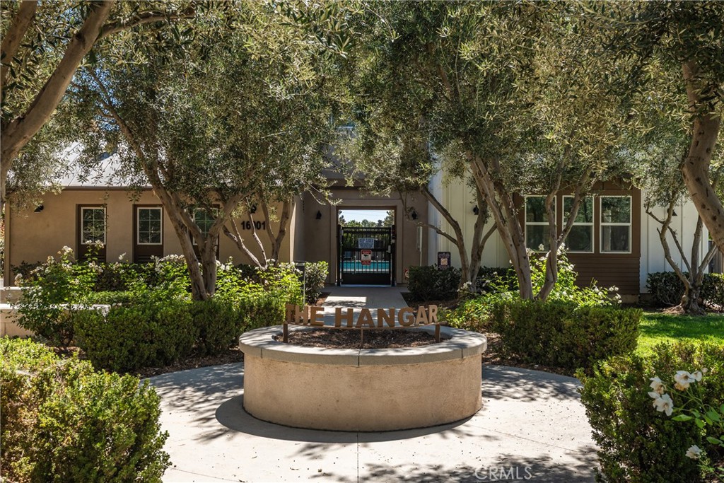 Residential community entrance with a circular THE HANGAR sign planter, gate, and mature trees.