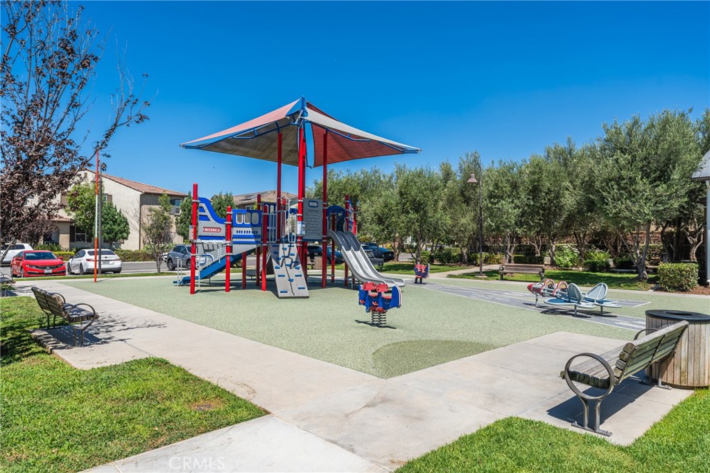 Neighborhood playground with colorful play equipment, shade canopy, paved paths, and benches.
