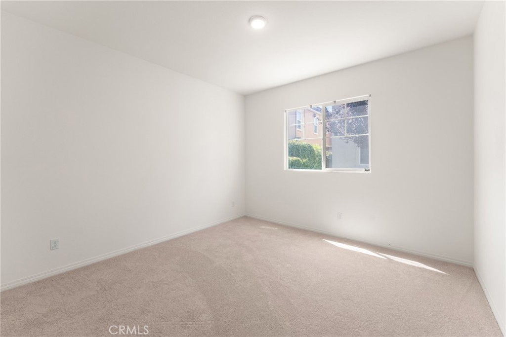 Empty bedroom with beige carpet and a window admitting daylight.