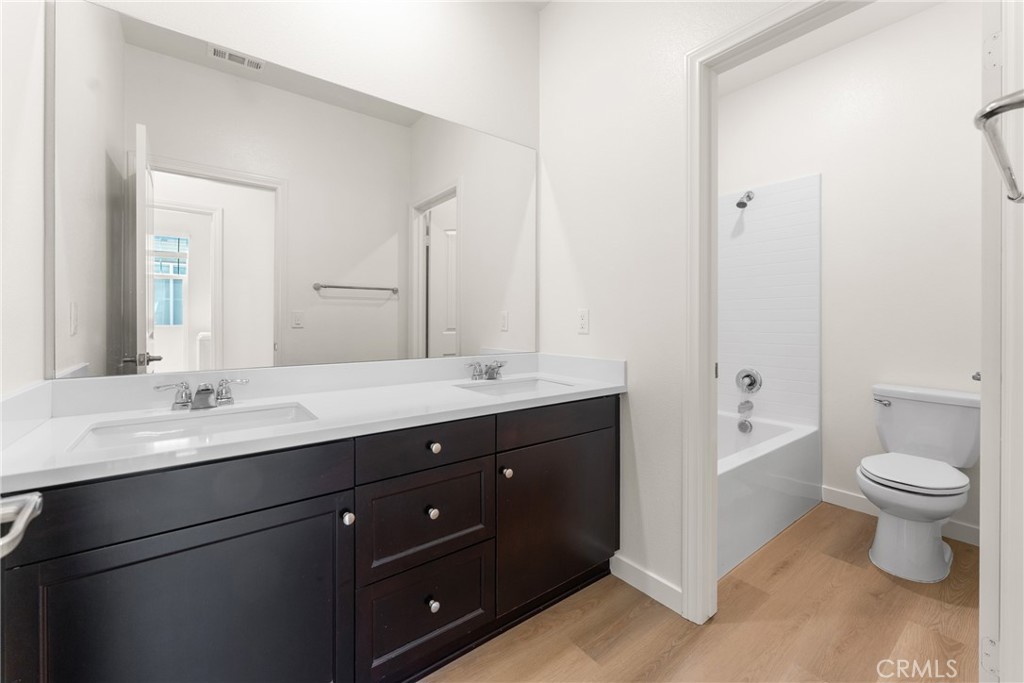 Bathroom with a dark double-sink vanity and an adjoining tub and toilet.
