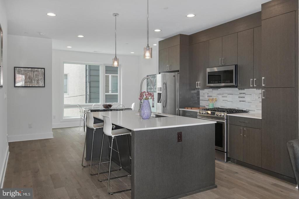 Modern kitchen with dark cabinetry, stainless steel appliances, and a large island with bar stools.