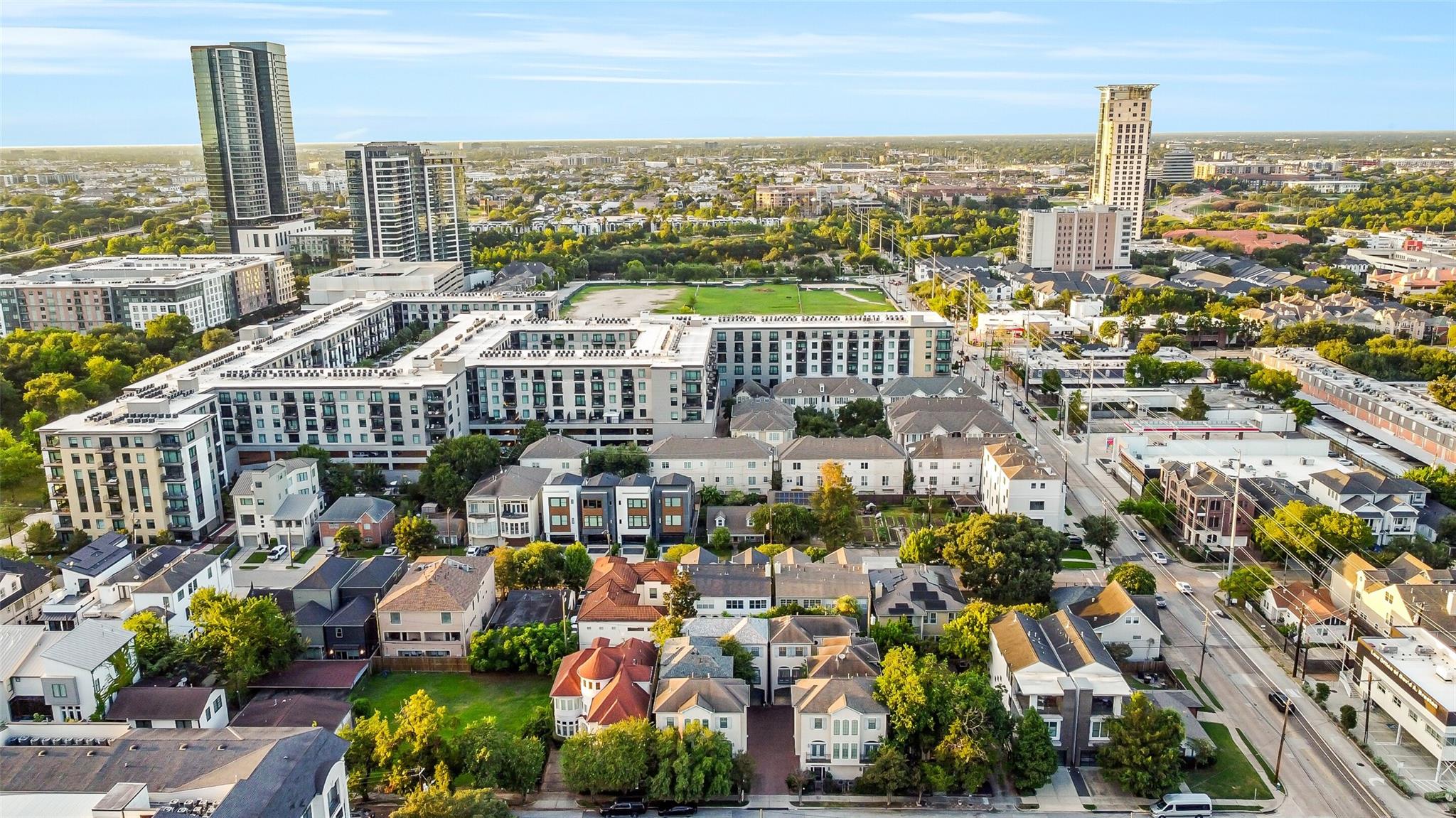 Aerial view of Houston homes and apartment buildings with high-rise towers in the distance.