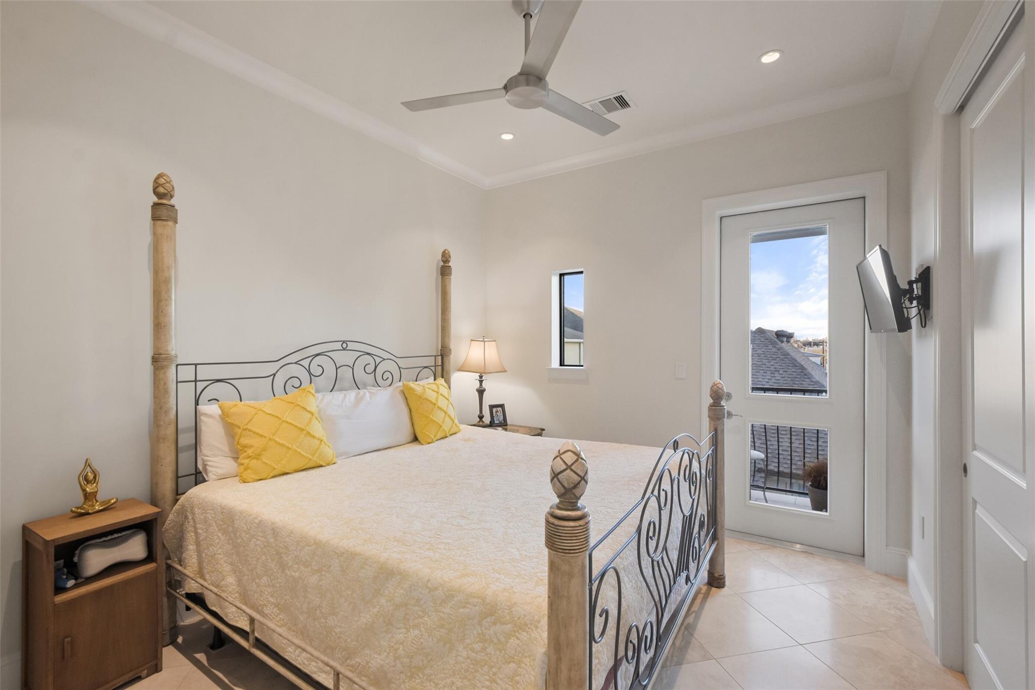 Bedroom with an ornate metal bed frame, yellow pillows, and a glass-paneled balcony door.