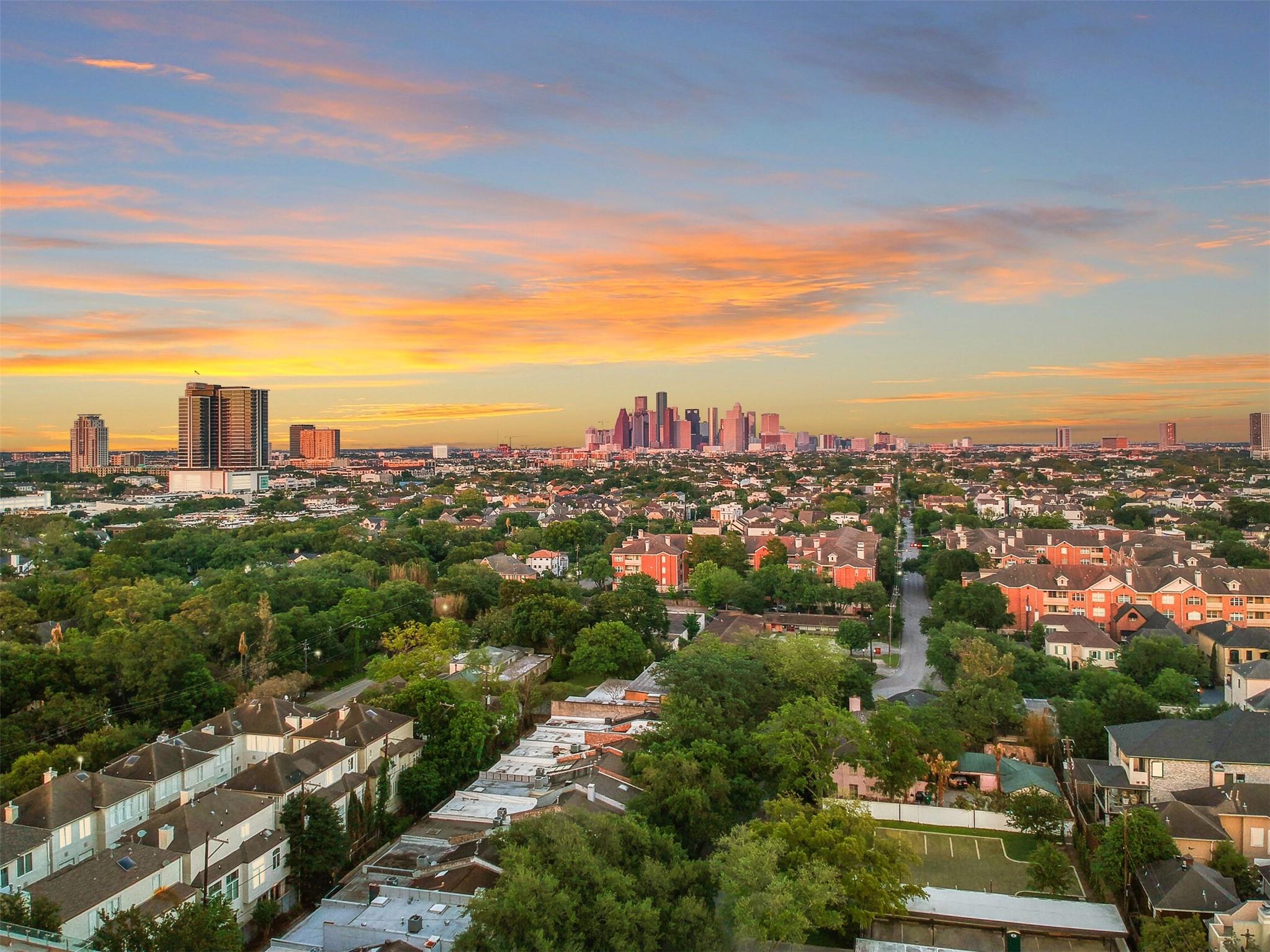 Aerial view of Houston neighborhoods and downtown skyline at sunset.