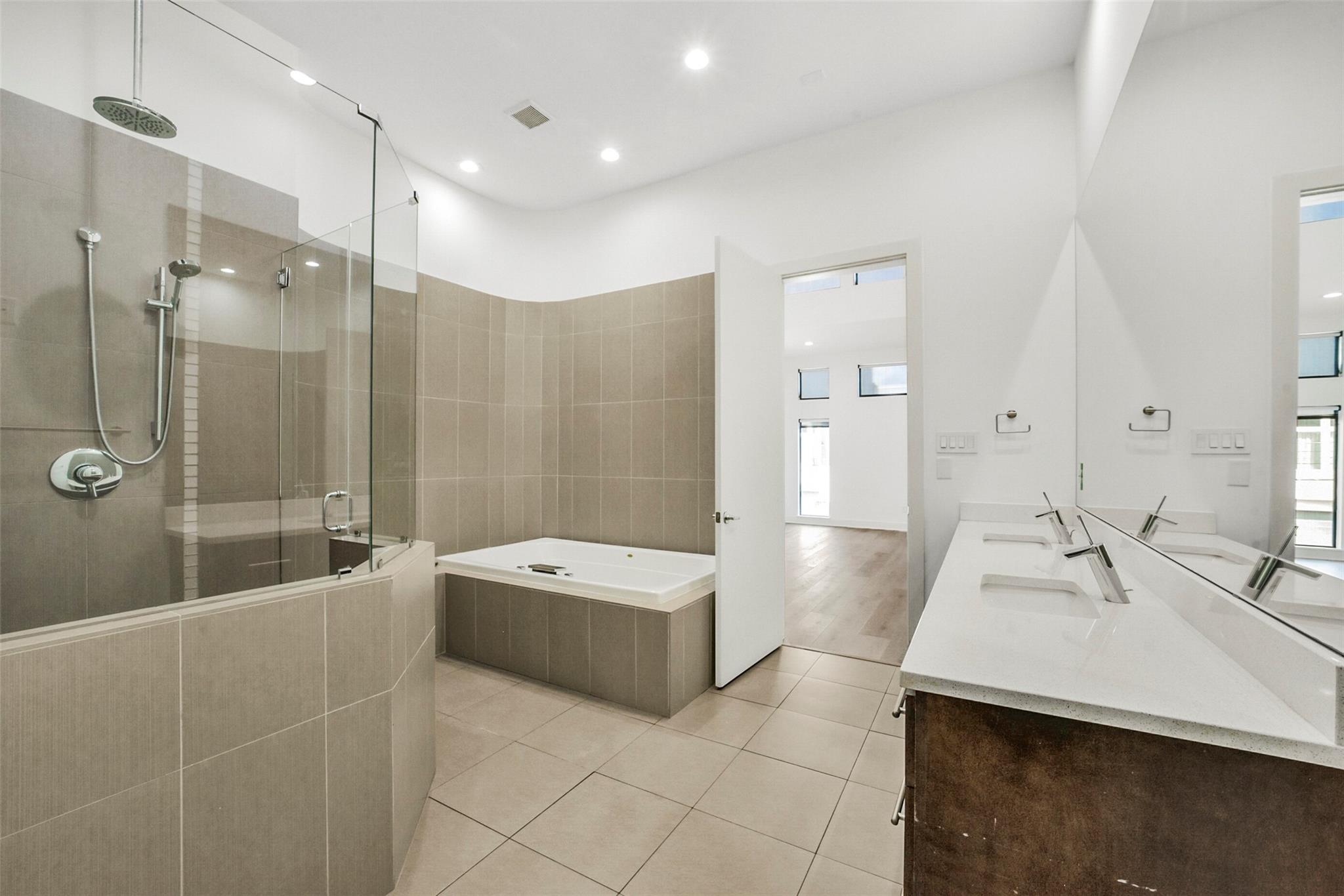 Modern bathroom with a glass shower, soaking tub, and long double-sink vanity.