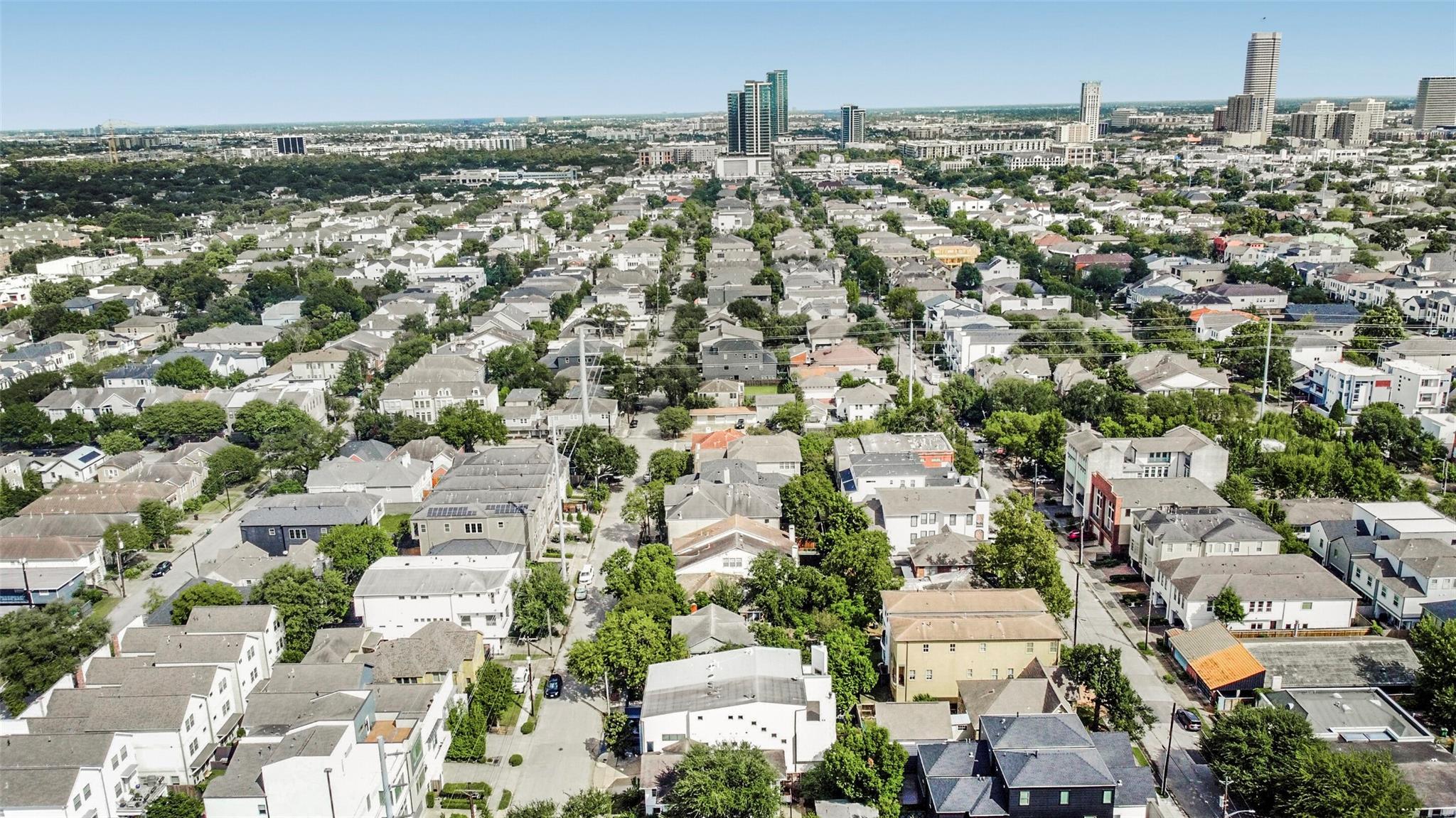 Aerial view of Houston homes and tree-lined streets with downtown high-rises on the horizon.