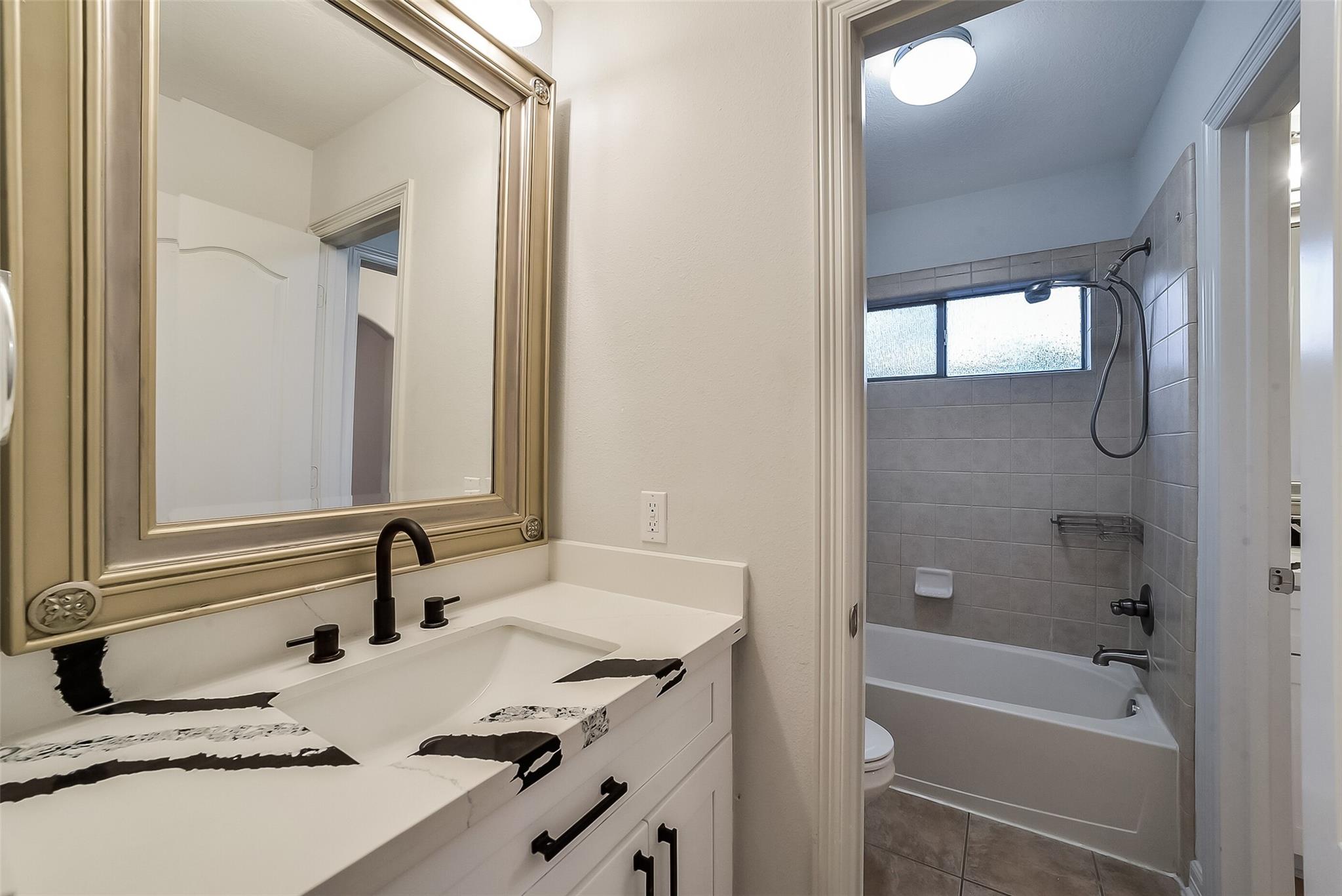 Bathroom with a bold black-and-white vanity counter and tiled tub-shower.